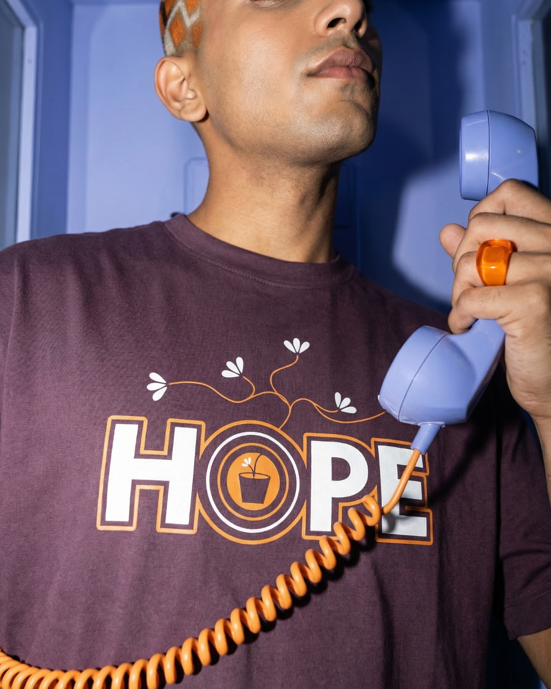Person wearing a shirt with 'HOPE' printed on it, holding a blue phone receiver.