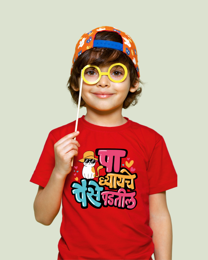 Child wearing a red t-shirt with colorful text and a cap, holding props against a plain background